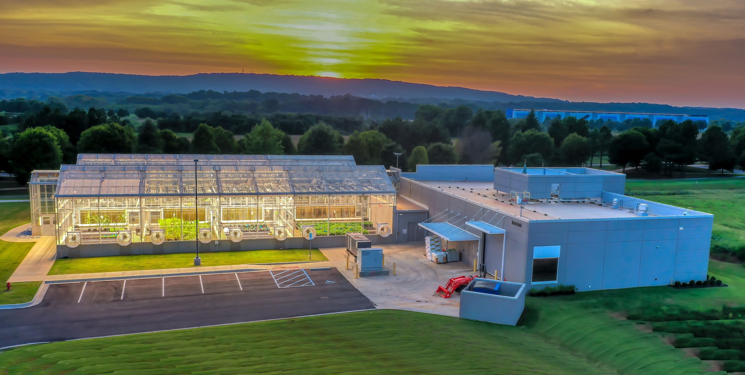 A greenhouse lit up at sunset
