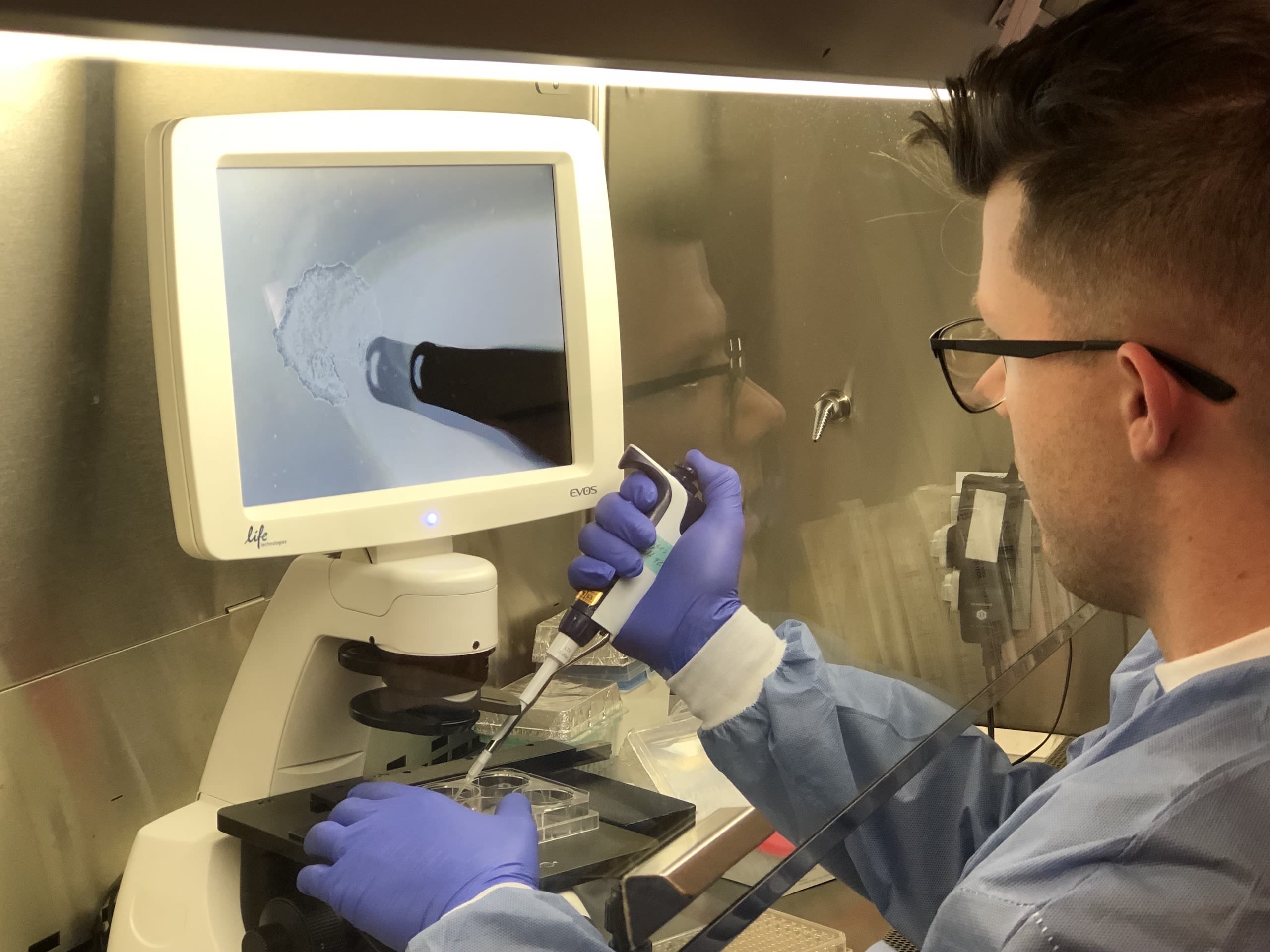 A man using a pipette at a microscope