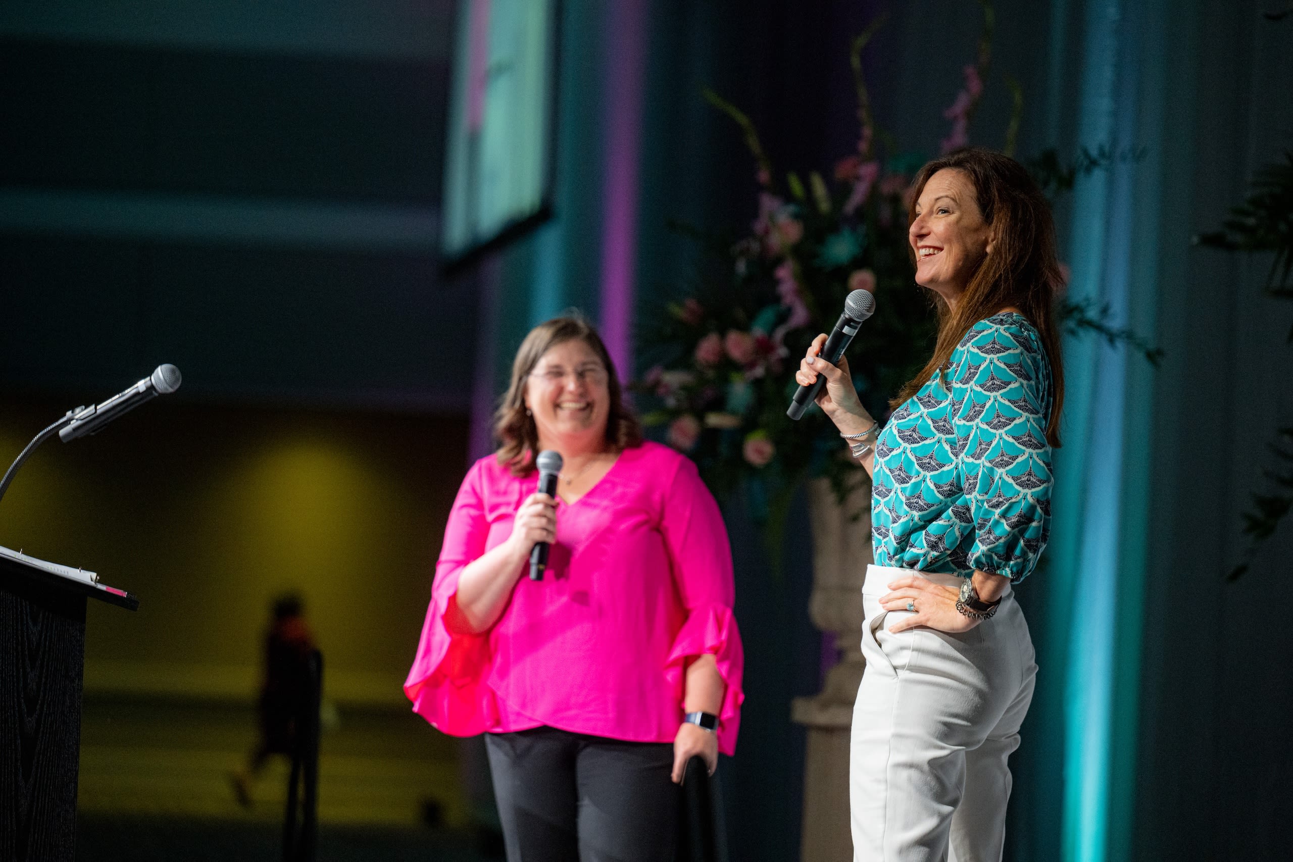 Two women presenting on a stage with microphones