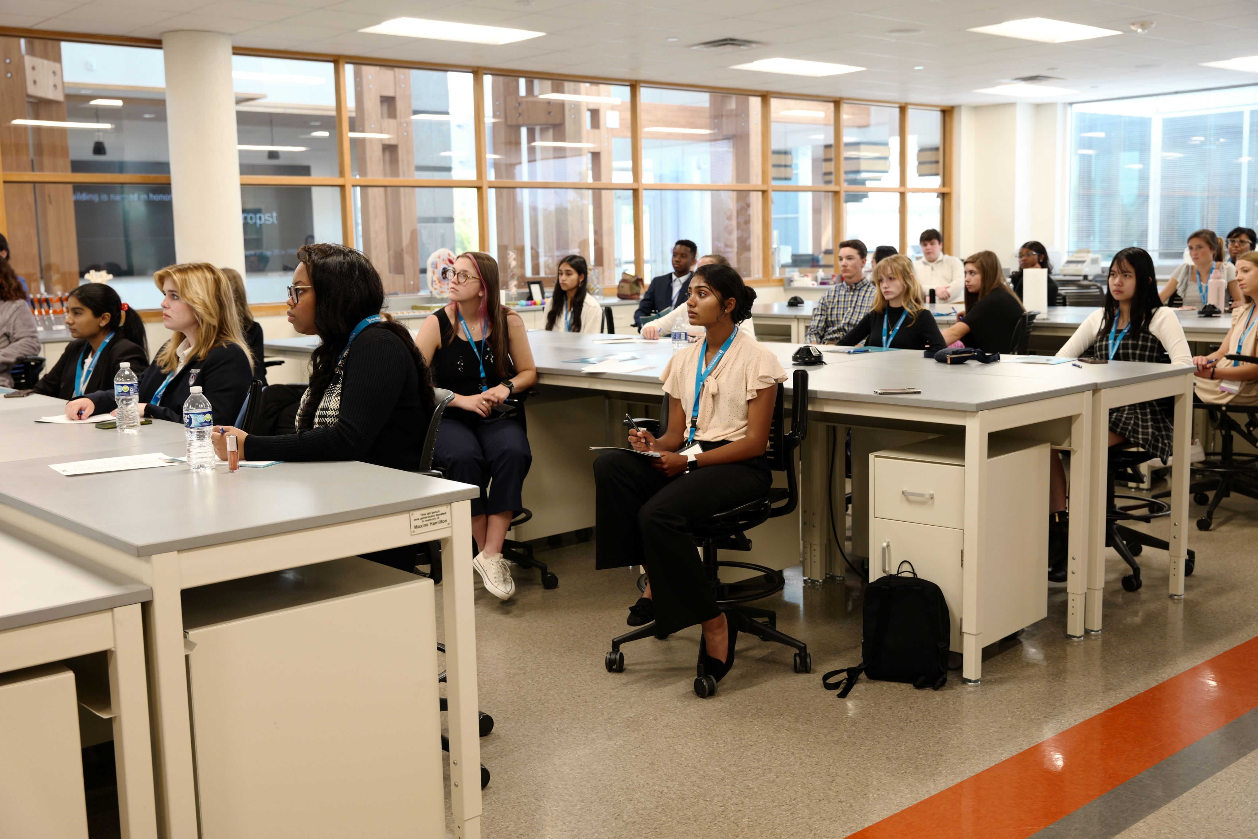High school students sitting at lab tables listening to a talk.